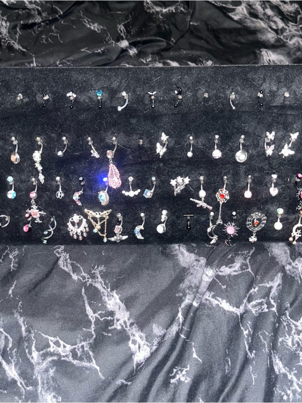 Belly button and eyebrow ring collection on black velvet display stand